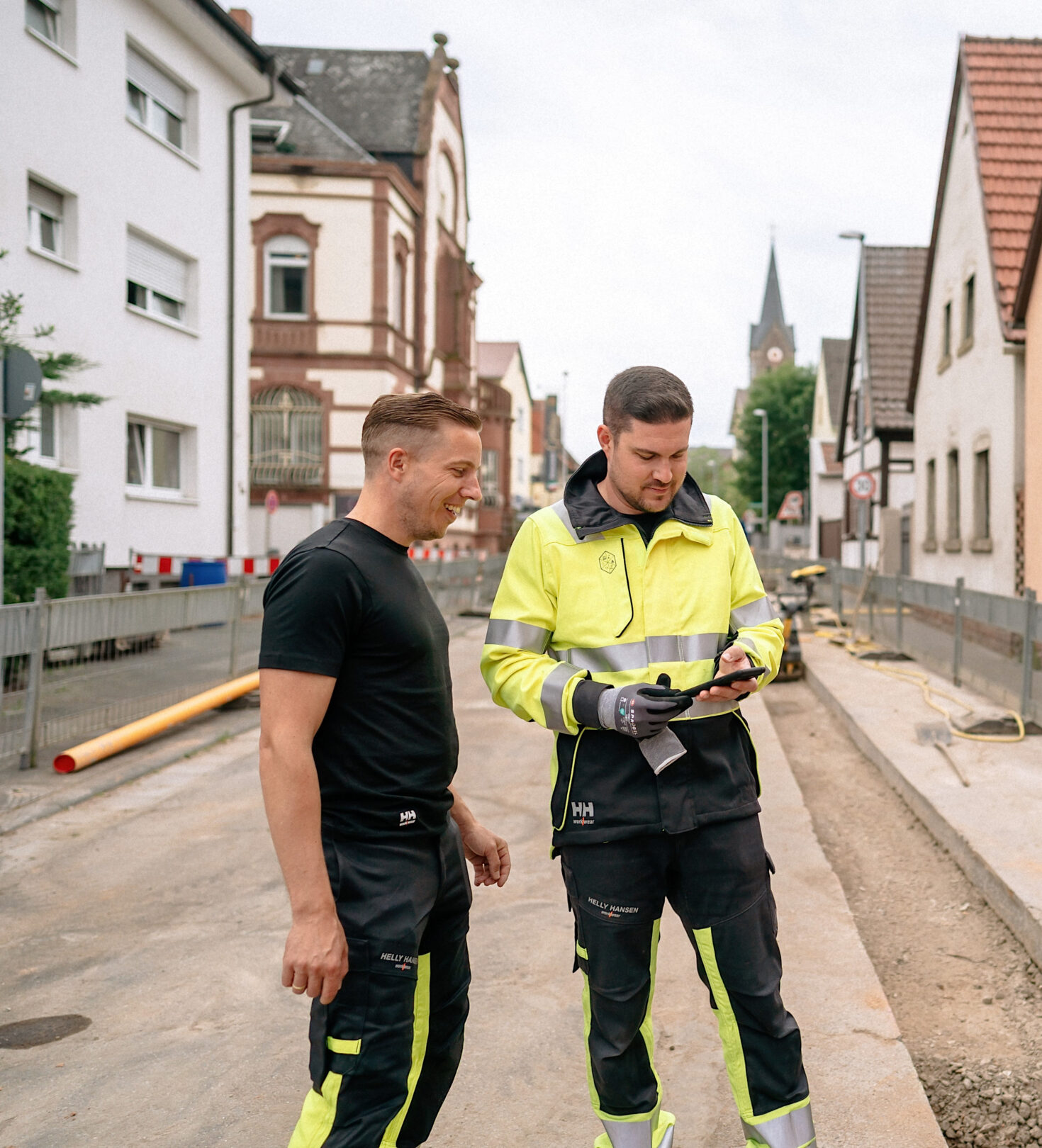 Zwei Mitarbeitende in Arbeitskleidung auf Baustelle