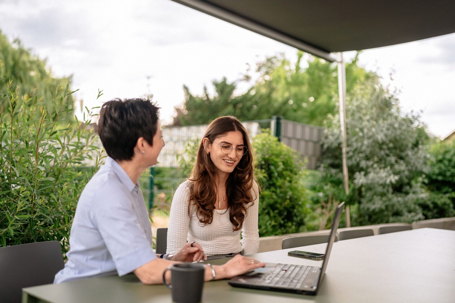 Zwei Mitarbeiterinnen vor Laptop im Außenbereich